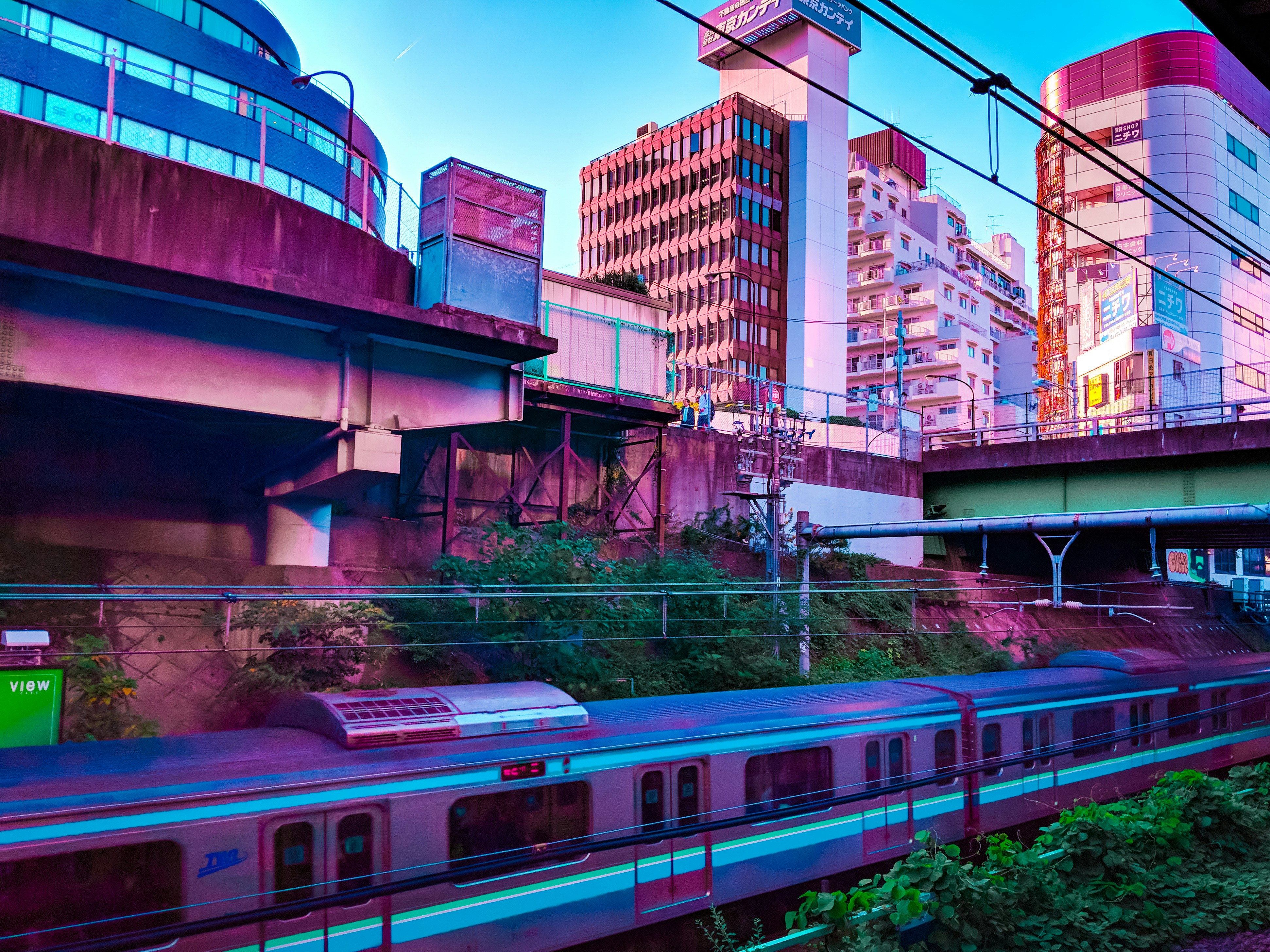 a train traveling past tall buildings under a bridge