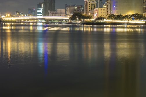 An evening skyline with glowing city lights and a calm river.