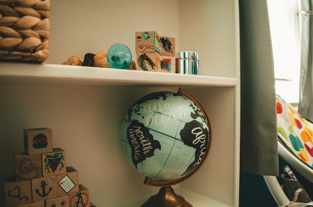 white and black desk globe on white wooden shelf