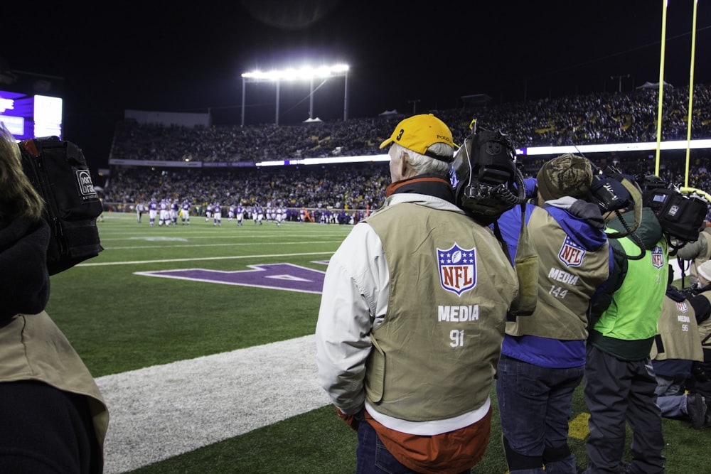 people standing and watching NFL game in green field