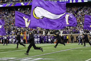 people running and holding Minnesota Vikings flags in green field