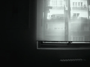 Minimalist black-and-white image of a quiet, sunlit room prepared for silent retreat participants.