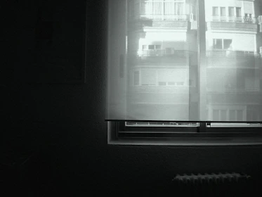 Minimalist black-and-white image of a quiet, sunlit room prepared for silent retreat participants.