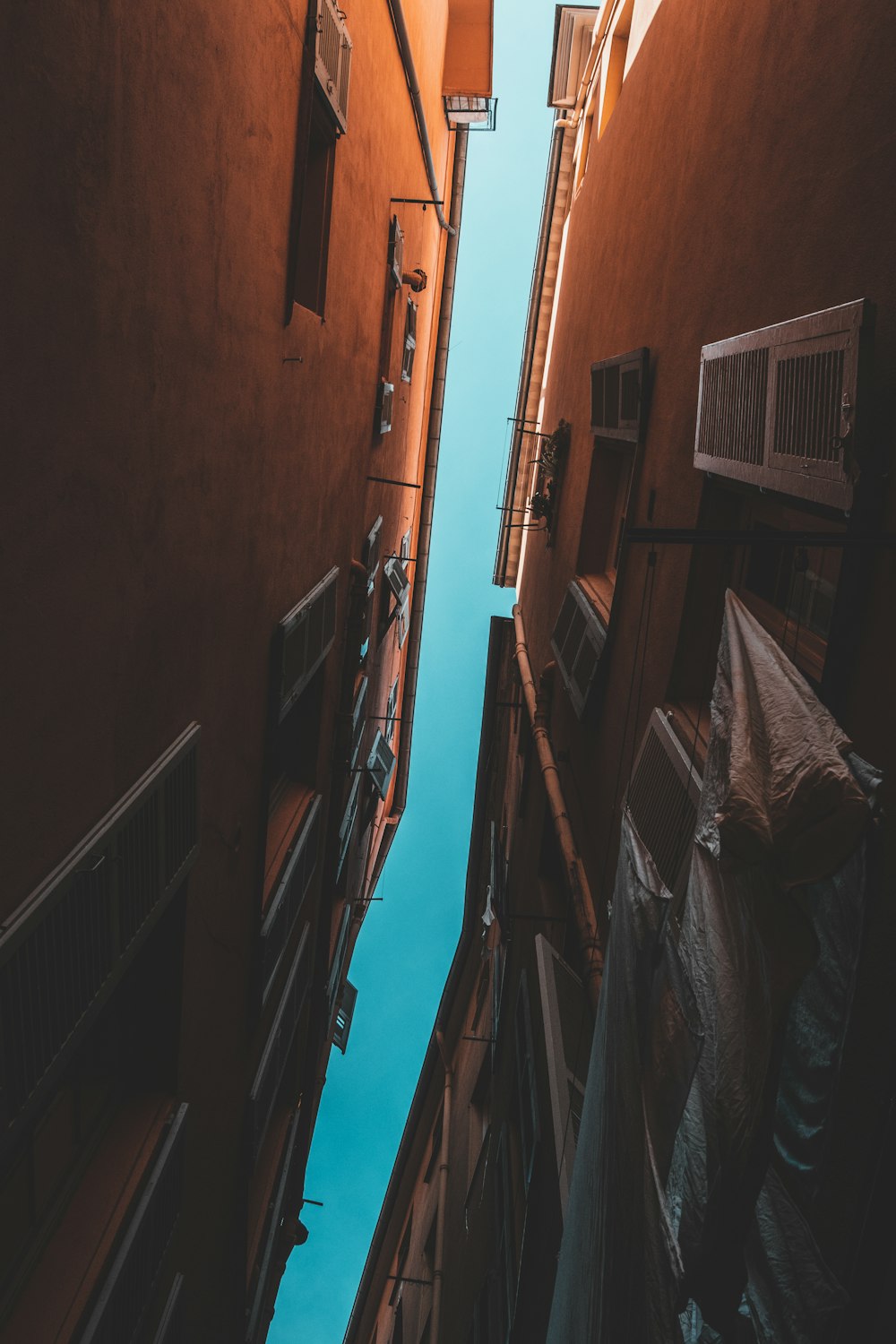 clear blue sky seen through narrow aisle in between brown buildings