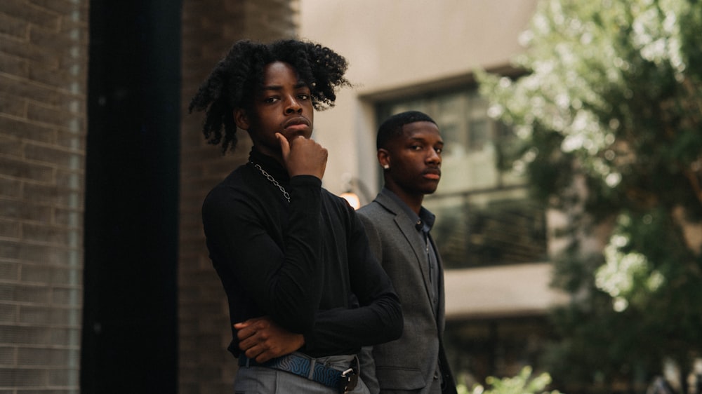 two men leaning on concrete wall