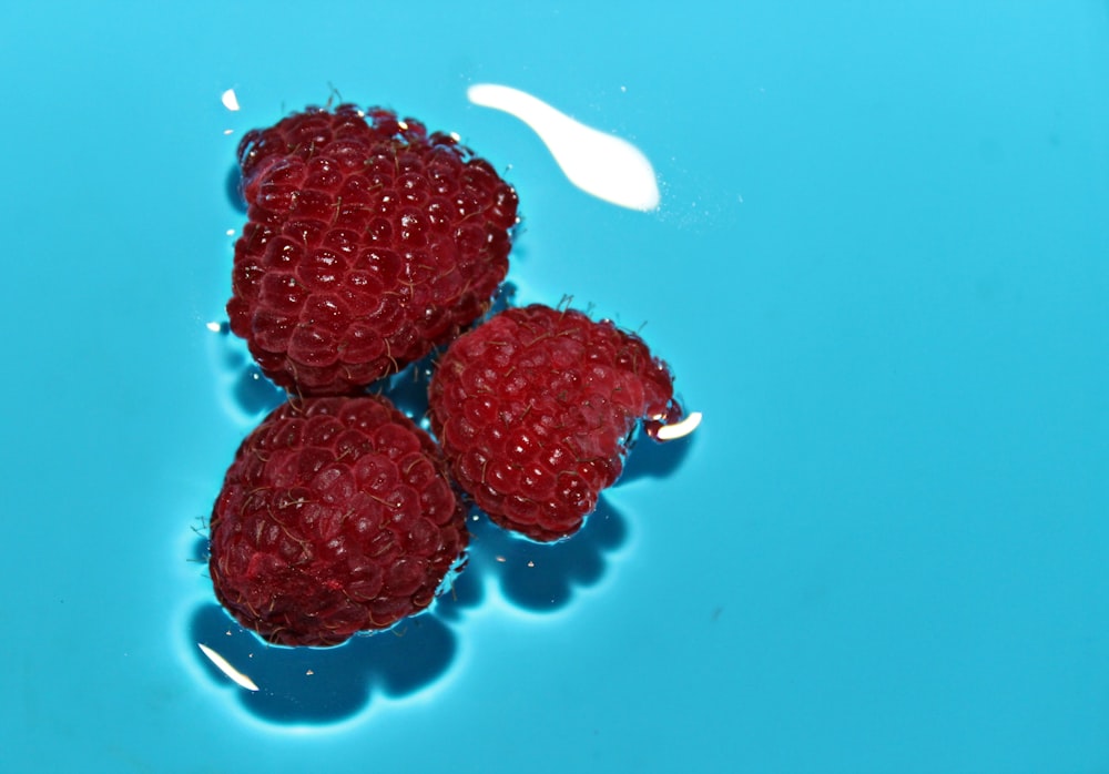 three raspberries floating on body of water