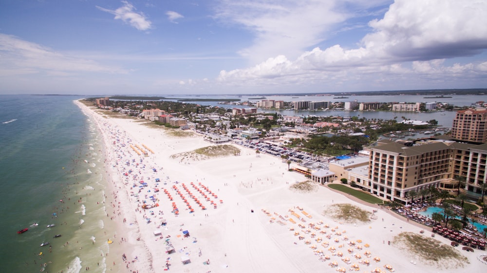 fotografia aerea di persone sulla spiaggia attraverso gli edifici durante il giorno