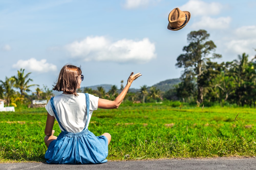 woman throwing up brown hat