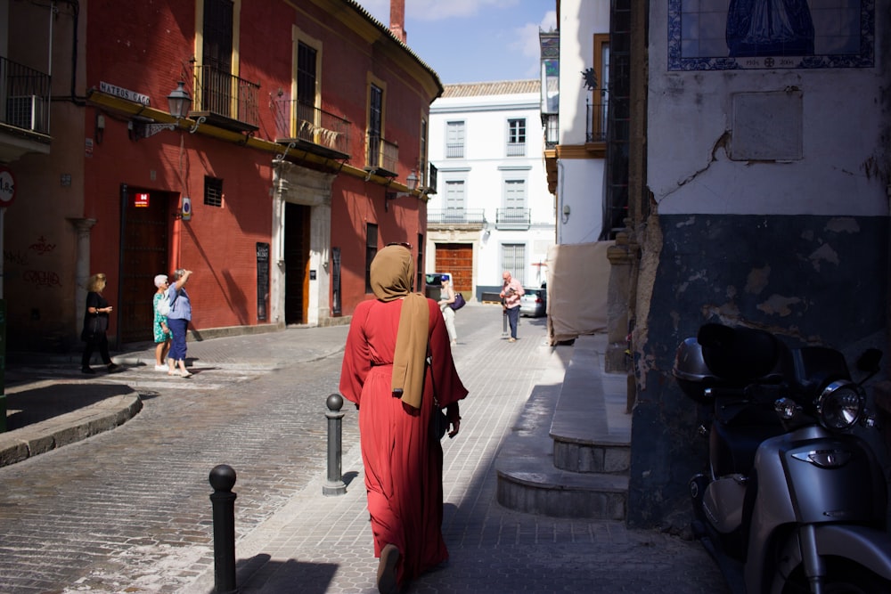 Mujer caminando al lado de la casa de hormigón blanco y rojo