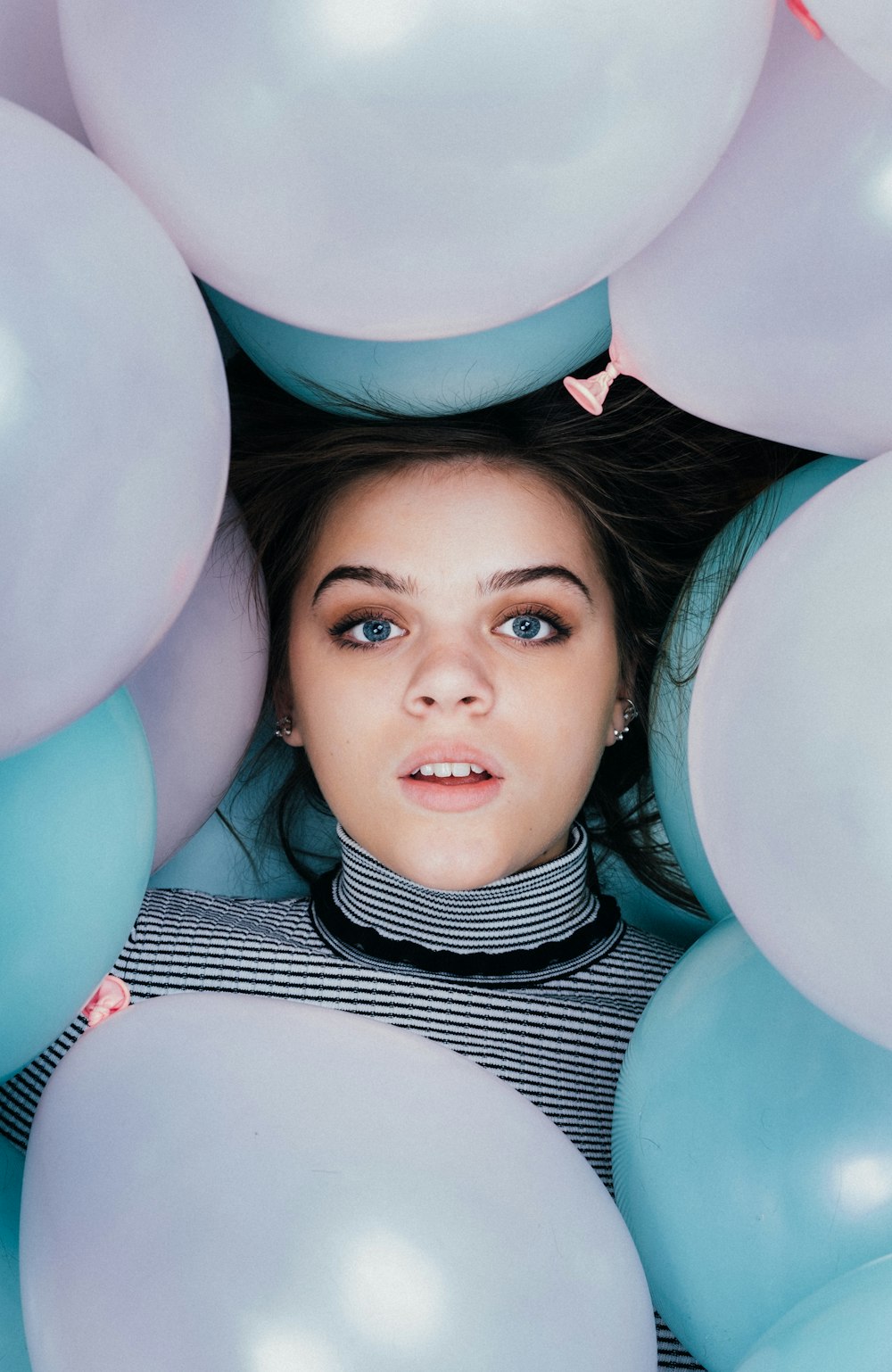 woman wearing striped turtle-neckline surrounded balloons