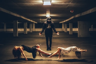 man standing between two women lying