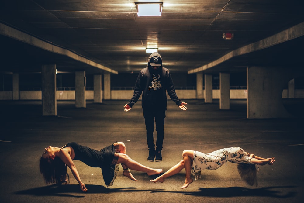 man standing between two women lying