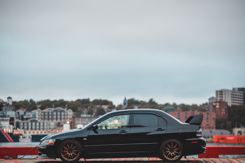 black sedan parked body of water