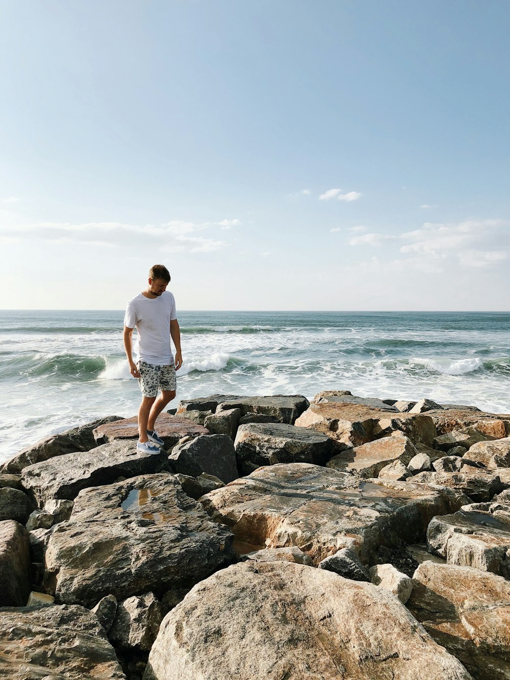 uomo in piedi sulle rocce vicino allo specchio d'acqua