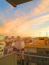Vibrant cityscape view from a stylish rental apartment balcony during sunset.