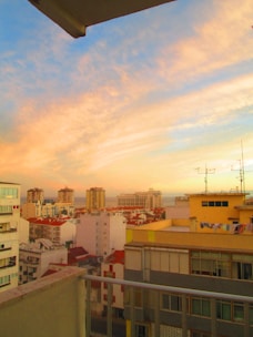Vibrant cityscape view from a stylish rental apartment balcony during sunset.
