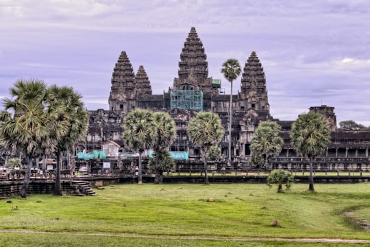 gray concrete building near green trees under cloudy sky at daytime in Angkor Wat Cambodia