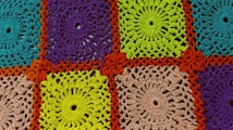A detailed crochet pattern composed of colorful squares. Each square is crafted with intricate designs, featuring spirals and loops. The colors include bright turquoise, purple, vibrant green, and beige, all framed by a bold orange border.