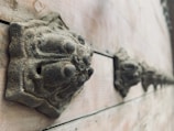 A series of ornately carved metal details are mounted along the surface of a weathered wooden surface. These round, decorative features have an aged, patinated look, suggesting they have withstood time and elements.