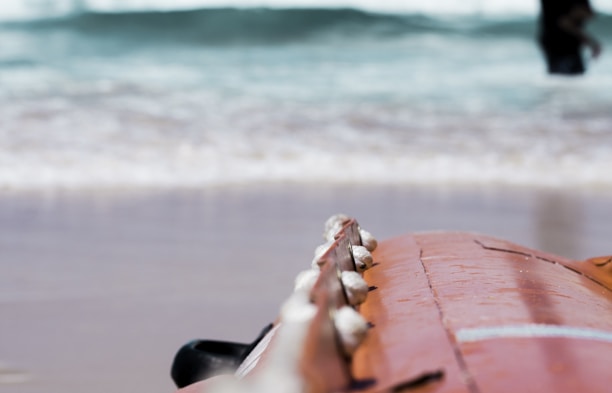 A close-up of a polished ChargerHub surfboard on the beach.