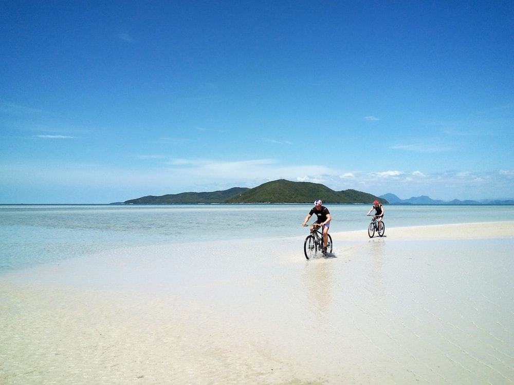 Dos hombres montando en bicicleta en la playa