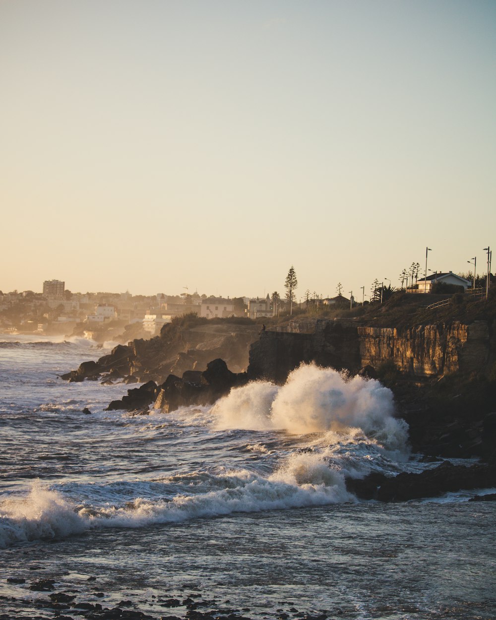 ocean wave crashing to rock island during golden hour