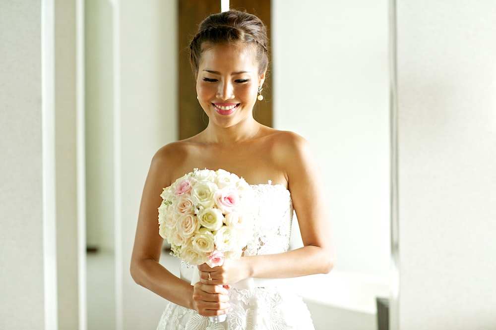 woman wearing white tube dress holding bouquet of flower