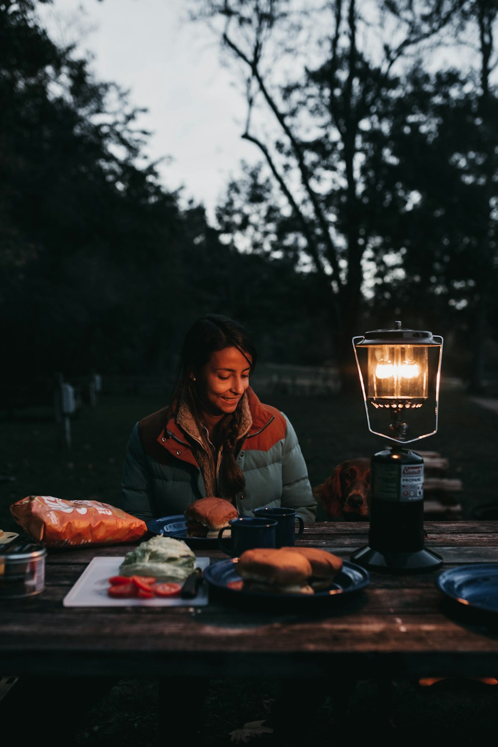 smiling woman sitting beside table with hamburger