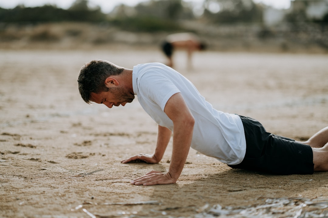 man doing push ups on sand