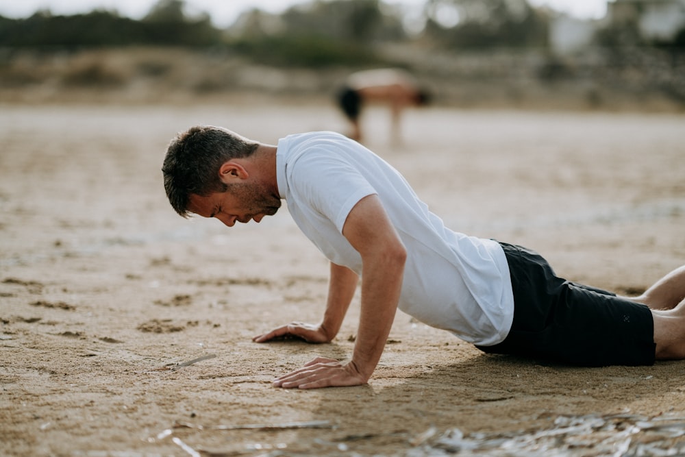 man doing push ups on sand