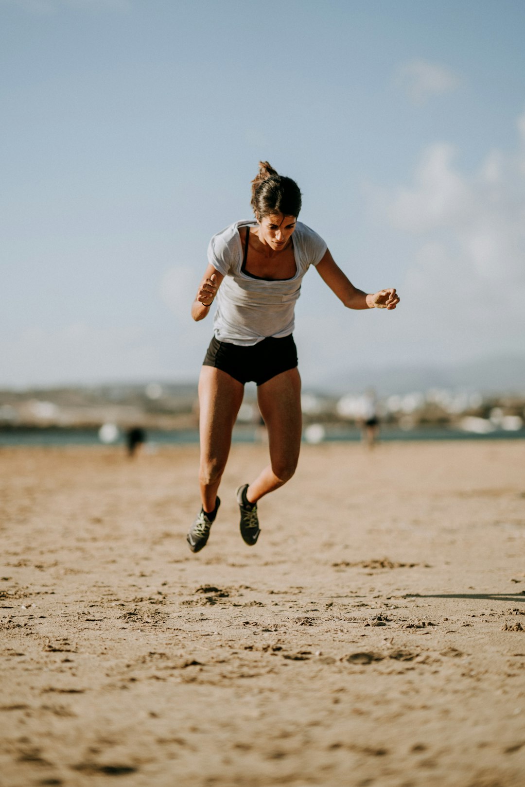 selective focus photo of woman jumping on seashore