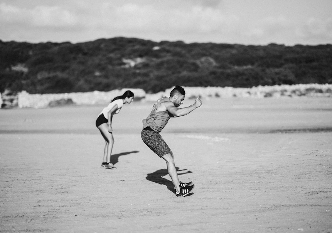 grayscale photo of man and woman jumping