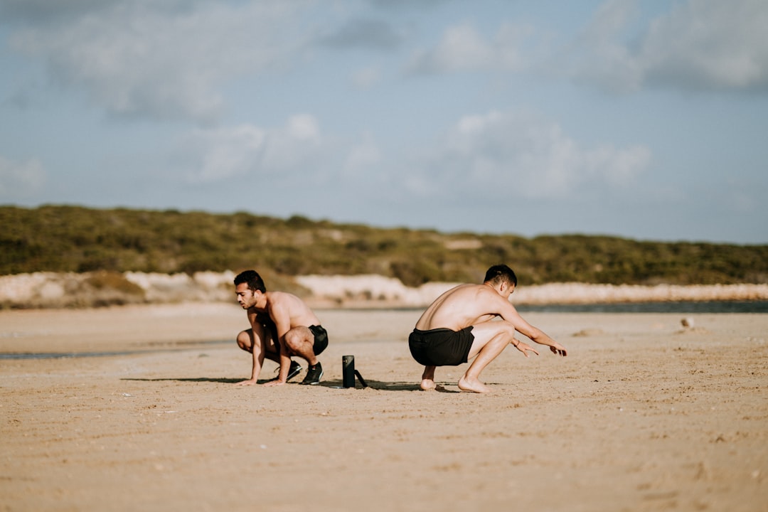 two men sitting on sand