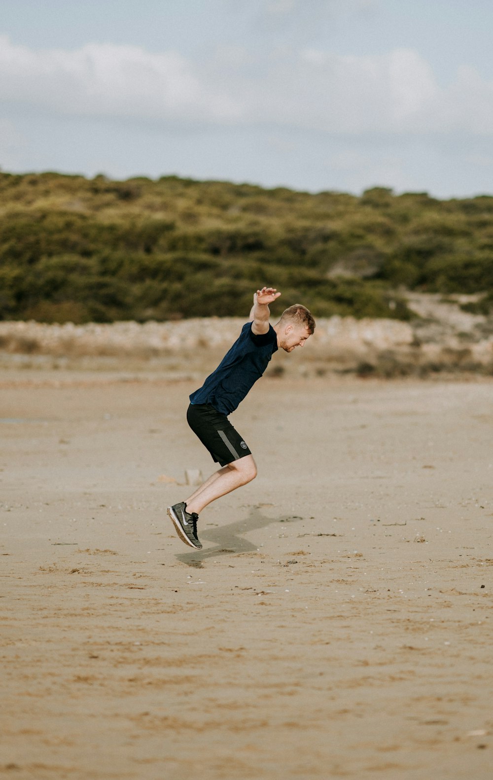 man jumping on sand at daytime