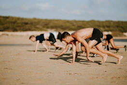 People practicing animal flow exercises outdoors near the ocean