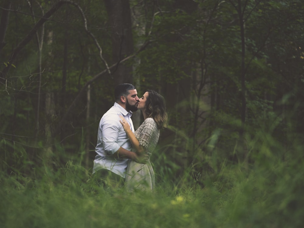 besando al hombre y a la mujer de pie en el campo de hierba verde
