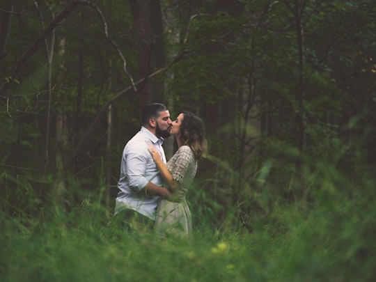 kissing man and woman standing on green grass field in Virginia Beach United States