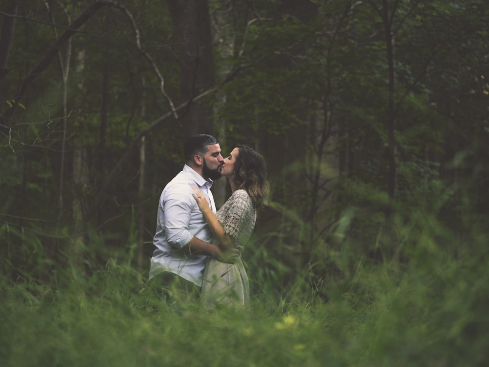 kissing man and woman standing on green grass field