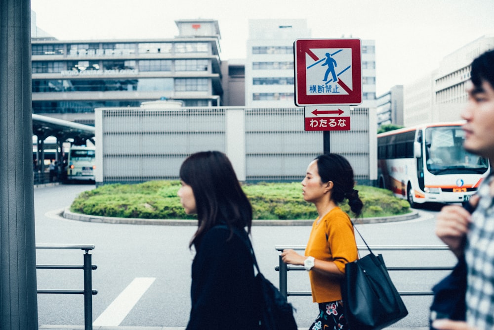 three people walking beside metal rails