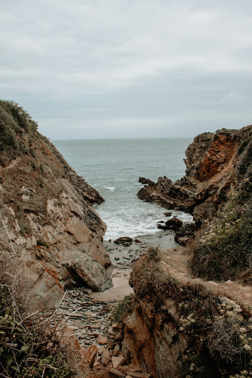 pathway between rock cliffs leading to the sea