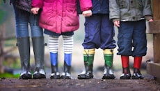 four children standing on dirt during daytime