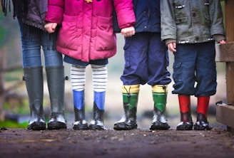 four children standing on dirt during daytime
