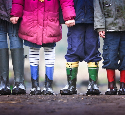 four children standing on dirt during daytime