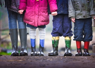 four children standing on dirt during daytime