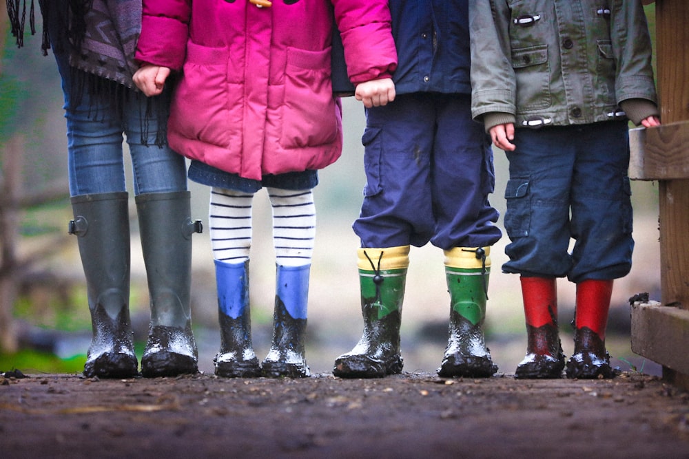 Cuatro niños parados en la tierra durante el día