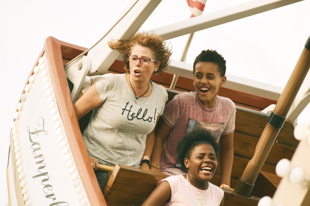 mulher, menino e menina montando passeio de barco de diversão