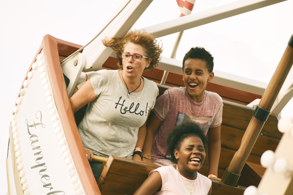 woman, boy, and girl riding amusement boat ride