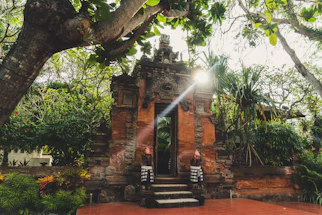 A serene Balinese villa entrance framed by lush tropical greenery and soft golden light.