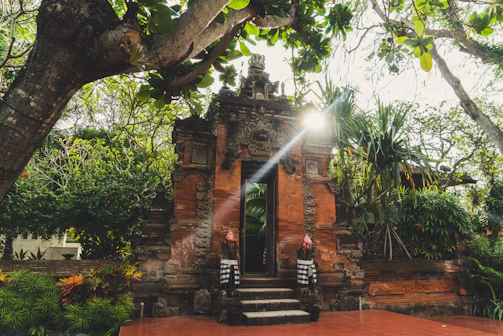 A serene Balinese villa entrance framed by lush tropical greenery and soft golden light.