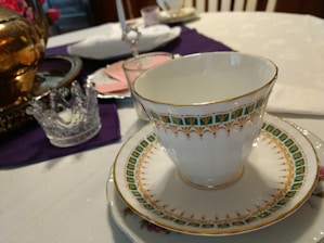 Elegant teacup set on a royal red and gold embroidered cloth with Rajasthan palace backdrop.